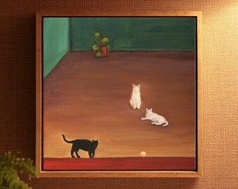 May include: A framed painting depicting two white cats and one black cat on a brown floor. One white cat sits upright, another lies down, and the black cat stands near a small ball. A green wall with a potted plant is visible in the background.