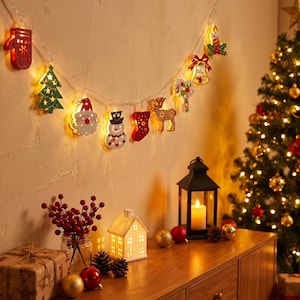 May include: A string of Christmas lights featuring wooden cutouts of a red mitten, green tree, Santa Claus, snowman, red stocking, reindeer, candy cane, bell, and candle, all illuminated by warm white LED lights against a wall.