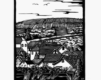 May include: A black and white linocut print depicting a rural landscape with a cluster of houses in the foreground and rolling hills in the background. The sky features stylized clouds and birds. The print is signed and numbered 24/24 by the artist.