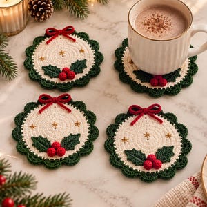 Puede incluir: Cuatro posavasos redondos de ganchillo con un centro color crema con pequeños detalles de estrellas doradas, un borde festoneado verde oscuro y un lazo de hilo rojo en la parte superior. Cada posavasos está decorado con tres bayas rojas y dos hojas de acebo.
