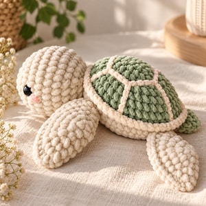 Può includere: Un peluche a forma di tartaruga realizzato all'uncinetto con testa e arti color crema dalla superficie testurizzata e irregolare. La tartaruga ha un guscio arrotondato color verde salvia tenue con bordi crema, piccoli occhi neri e guance rosa.