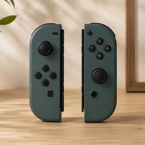 Op de afbeelding: Een paar mat saliegroene gamecontrollers met zwarte analoge sticks, richtingsknoppen en actieknoppen gelabeld met X, Y, A en B. De controllers staan verticaal opgesteld en tonen hun strakke, uniforme ontwerp en functionele indeling voor gameconsoles.