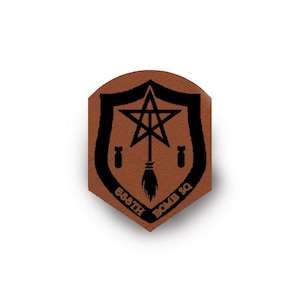 May include: A brown leather-like patch shaped like a shield with a black printed design. The design features a central star and broomstick emblem, two small bomb icons on the sides, and the text 588TH BOMB SQ curved along the bottom edge.