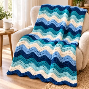 May include: A crochet blanket featuring a repeating wavy pattern in shades of dark blue, medium blue, light blue, and cream. The thick, textured yarn creates a soft, rippled appearance across the entire surface of the rectangular throw.