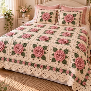 May include: A cream-colored crochet bedspread and two matching square pillows featuring a repeating pattern of three-dimensional pink roses with green leaves. The edges of the bedspread are finished with a scalloped border and small pink flowers.