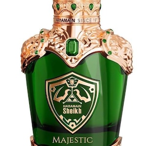 Könnte beinhalten: Ein grüner Glasparfümflakon mit einem goldfarbenen, kronenförmigen Verschluss, einer zentralen smaragdgrünen Verzierung, goldenen Schulterdetails und einem schildförmigen Emblem mit dem Text HARAMAIN SHEIKH und dem Wort MAJESTIC.