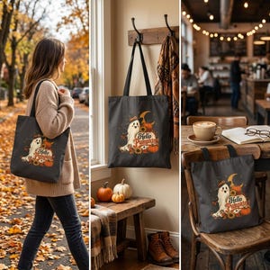 Puede incluir: Un bolso tote gris oscuro con un gráfico de un fantasma con sombrero de bruja, rodeado de calabazas, girasoles y una luna creciente, con el texto Hello Pumpkin impreso en una fuente naranja estilizada en la parte frontal.