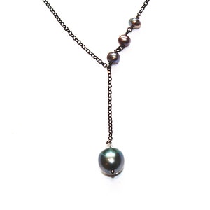 May include: A black chain necklace with a single large black pearl pendant and four smaller black pearls on the chain.
