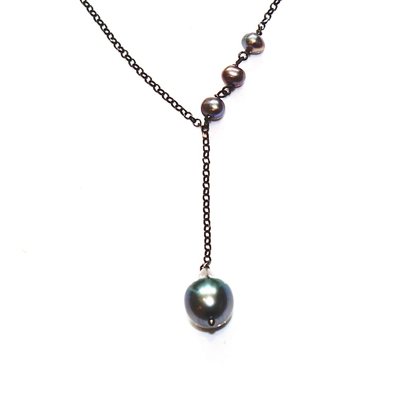 May include: A black chain necklace with a single large black pearl pendant and four smaller black pearls on the chain.