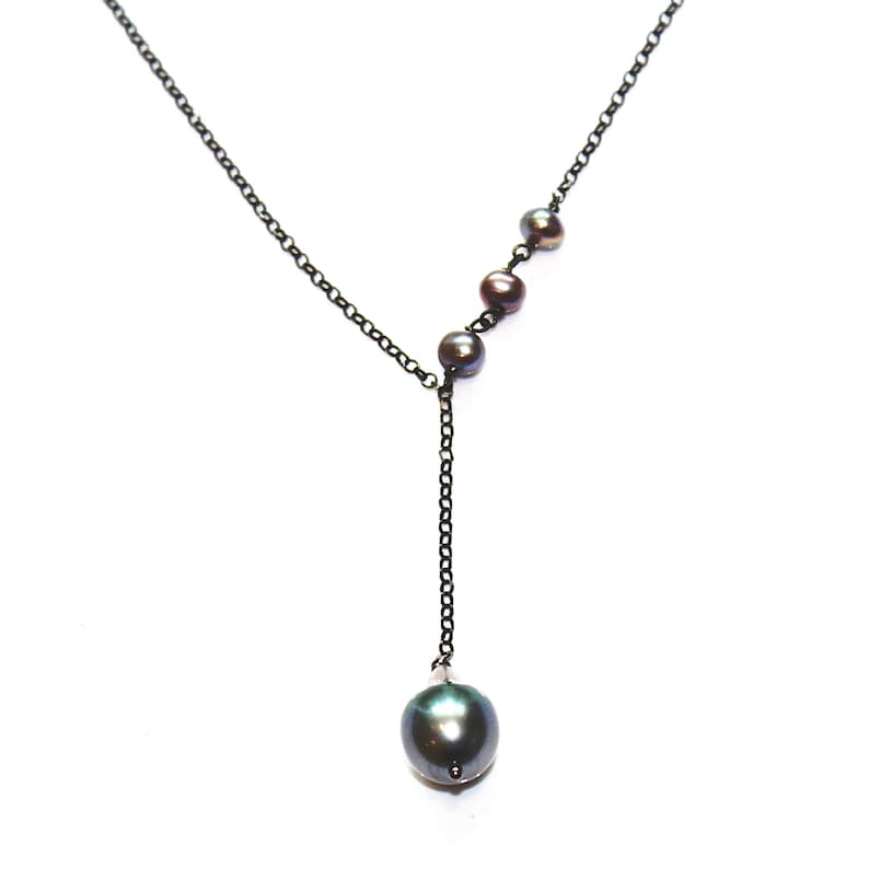 May include: A black chain necklace with a single large black pearl pendant and four smaller black pearls arranged in a diagonal line.