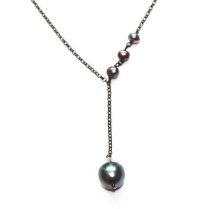 May include: A black chain necklace with a single large black pearl pendant and four smaller black pearls on the chain.