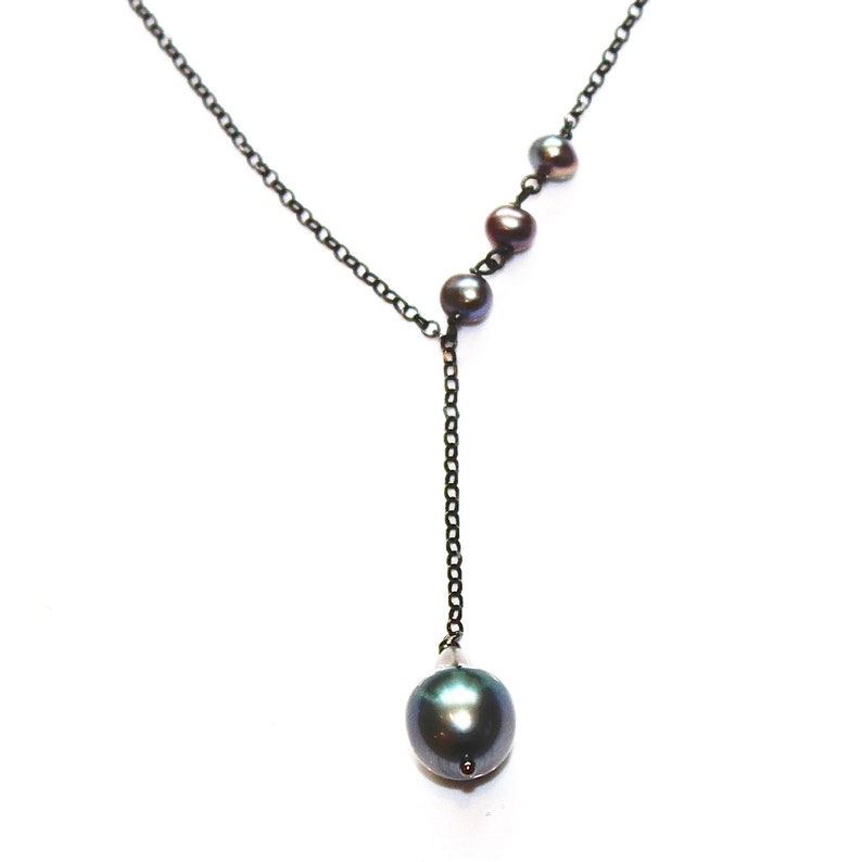 May include: A black chain necklace with a single large black pearl pendant and four smaller black pearls on the chain.