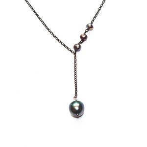 May include: A black chain necklace with a single large black pearl pendant and four smaller black pearls along the chain.