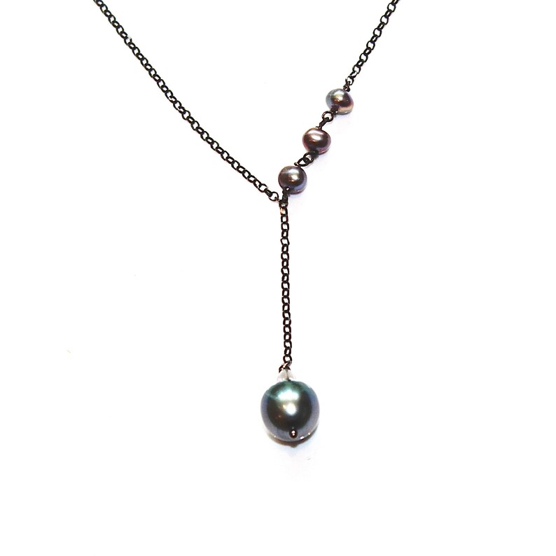 May include: A black chain necklace with a single large black pearl pendant and four smaller black pearls along the chain.