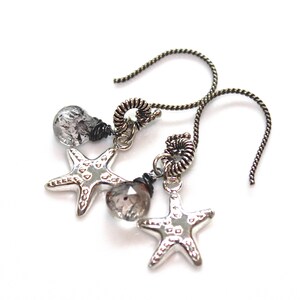 May include: Silver starfish earrings with clear quartz crystals and black wire accents. The earrings have a simple, elegant design and are perfect for everyday wear.