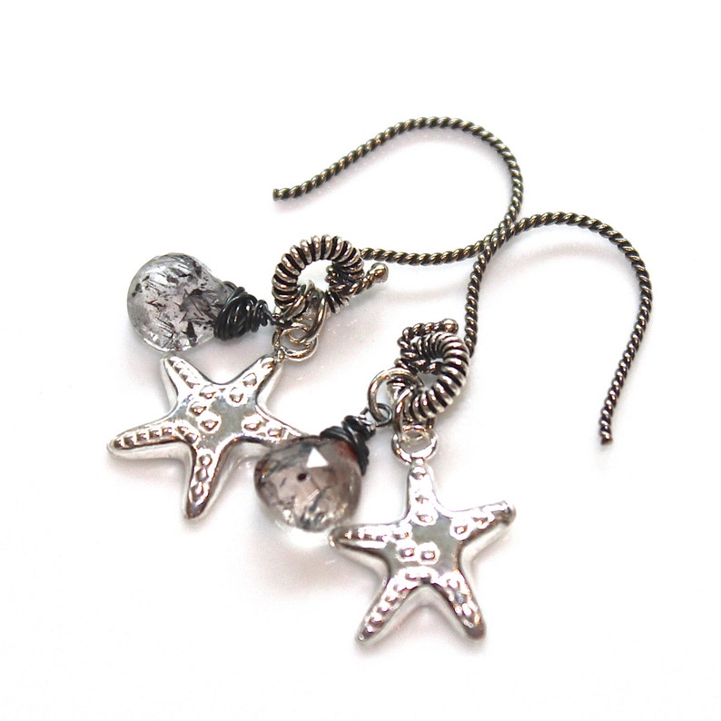 May include: Silver starfish earrings with clear quartz crystals and black wire accents. The earrings have a simple, elegant design and are perfect for everyday wear.