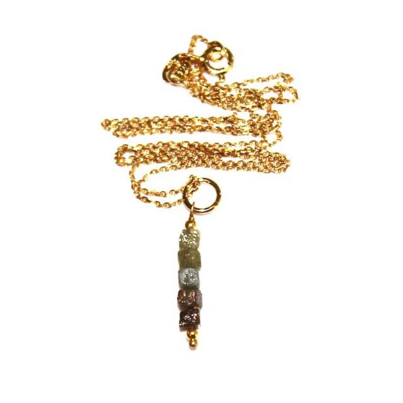 K&ouml;nnte beinhalten: Eine goldene Kettenkette mit einem Anh&auml;nger aus einer Reihe kleiner, rauer, grauer und brauner Diamanten.