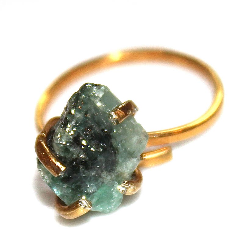 Pu&ograve; includere: Un anello d'oro con un grande smeraldo verde grezzo incastonato al centro. Lo smeraldo &egrave; una pietra naturale grezza di colore verde scuro e aspetto leggermente nuvoloso.