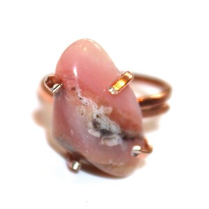 May include: A pink opal ring with a copper band and gold accents. The opal is a natural stone with a unique pattern and colour.