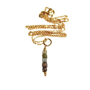 K&ouml;nnte beinhalten: Eine goldene Kettenkette mit einem Anh&auml;nger aus einer Reihe kleiner, rauer, mehrfarbiger Diamanten.