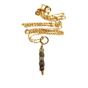 K&ouml;nnte beinhalten: Eine goldene Kettenkette mit einem Anh&auml;nger aus einer Reihe kleiner, quadratischer, grauer, brauner und gr&uuml;ner roher Diamanten.