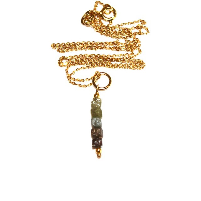 K&ouml;nnte beinhalten: Eine goldene Kettenkette mit einem Anh&auml;nger aus einer Reihe kleiner, rauer, gr&uuml;ner, brauner und grauer Diamanten.