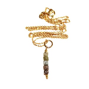 K&ouml;nnte beinhalten: Eine goldene Kettenkette mit einem Anh&auml;nger aus einer Reihe kleiner, quadratischer, roher, mehrfarbiger Diamanten.