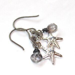 May include: Silver dangle earrings with two silver starfish charms and two clear quartz teardrop crystals.