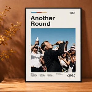 May include: A framed movie poster for Another Round, 2020. The design features the title in bold black text, a central photograph of a person drinking from a bottle surrounded by others in white shirts and caps, and small text listing the cast and director.