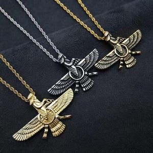 May include: Three necklaces featuring Faravahar pendants on twisted rope chains. One pendant is silver-toned, while the other two are gold-toned. Each pendant depicts a winged figure centred within a circle, showcasing detailed feather textures.