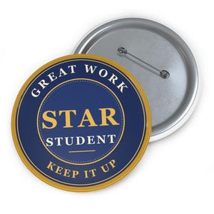 May include: A circular pin-back button featuring a dark blue background with a gold border. The text reads GREAT WORK in an arc at the top, STAR STUDENT in the centre, and KEEP IT UP in an arc at the bottom. The back shows a metal pin mechanism.