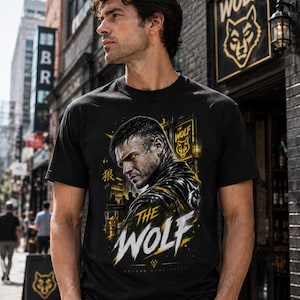 May include: A black short-sleeve t-shirt featuring a graphic print of a man with glowing yellow eyes. The design includes the text "THE WOLF" in large white letters, a small glass of amber liquid, and a Japanese character for wolf in yellow.