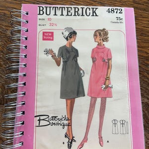 May include: A Butterick 4872 sewing pattern booklet with a spiral binding. The cover features illustrations of two dresses, one gray and one pink, with the text Butterick, 4872, Size 10, Bust 32 1/2, New Sizing, and Butterick Boutique.
