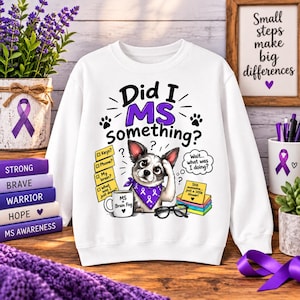 Op de afbeelding: Een wit sweatshirt met lange mouwen en een afbeelding van een hond met een paarse lint-bandana. De tekst luidt Did I MS something? met illustraties van een mok met MS Brain Fog, memoblaadjes en een bril op een witte achtergrond.