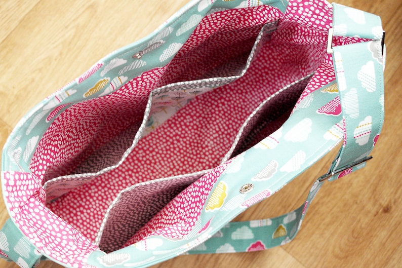 May include: A turquoise and white fabric tote bag with a pink and white polka dot lining. The bag has multiple interior pockets and a long adjustable strap.