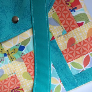 May include: A turquoise and multi-coloured patchwork tote bag with a turquoise strap. The bag has a flap pocket on the front with a silver button.