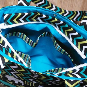 May include: A black and white chevron patterned tote bag with a turquoise blue lining and a zipper closure. The bag has multiple pockets and a handle.