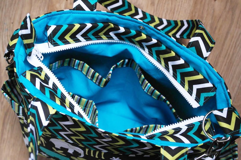 May include: A black and white chevron patterned tote bag with a turquoise blue lining and a zipper closure. The bag has multiple pockets and a handle.