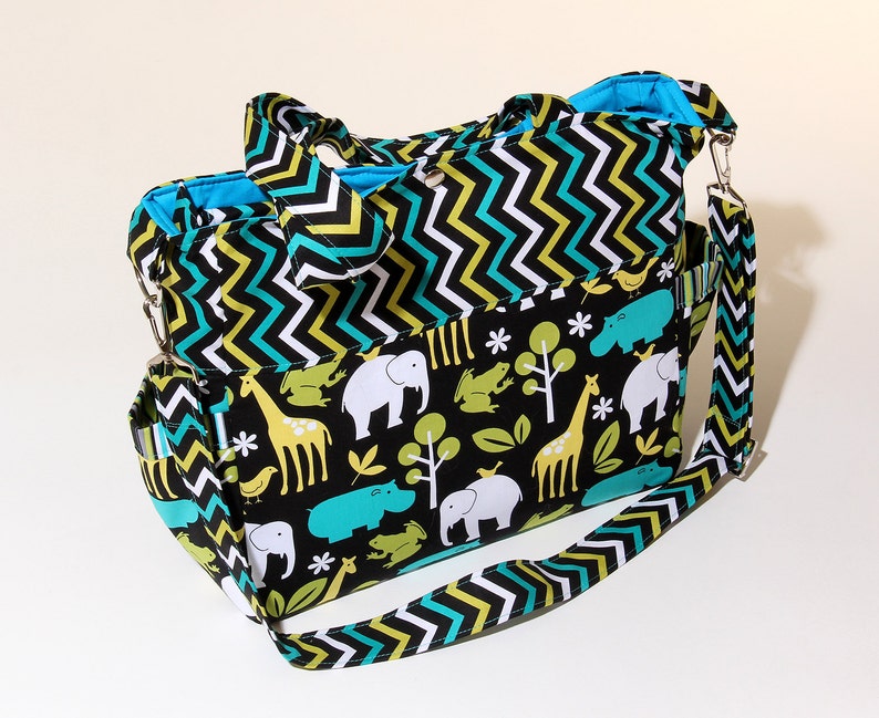 May include: A black, green, and blue chevron patterned tote bag with a long shoulder strap. The bag features a whimsical animal print with giraffes, elephants, hippos, and frogs.