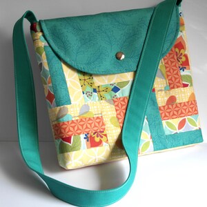 May include: A teal patchwork crossbody bag with a flap closure and a teal strap. The bag is made of various fabrics with geometric patterns in shades of yellow, orange, green, and red.