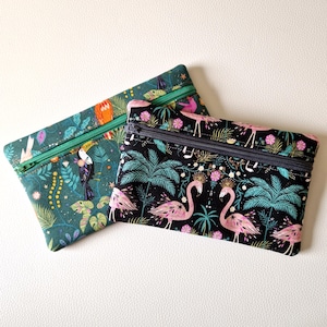 May include: Two zippered pouches with tropical prints. One pouch is green with toucans and palm trees, the other is black with pink flamingos and palm trees.