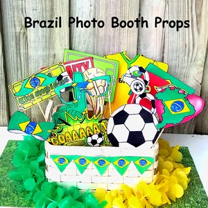 May include: A set of Brazil-themed photo booth props, including a soccer ball, a green and yellow bow tie, a pair of glasses, a sign that says "Champions", and a sign that says "GOAAAAAAAAL". The props are in a white wicker basket with green and yellow Brazilian flag bunting.