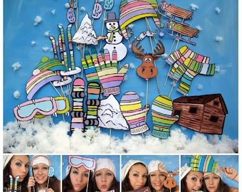 May include: A set of colorful winter-themed photo booth props, including a snowman, a moose, mittens, a cabin, skis, and a hat. The props are made of paper and are attached to sticks.