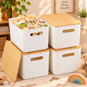 Puede incluir: Cuatro cajas de almacenamiento rectangulares blancas con textura trenzada y tapas de madera clara. Una caja está abierta y llena de bloques de madera. Cada caja tiene asas laterales integradas. El conjunto está apilado.