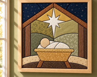 May include: A square framed fabric wall art piece featuring a quilted nativity scene. The design depicts a manger with a swaddled figure under a large white star, set against a dark blue starry sky and patterned green and brown fabric panels.