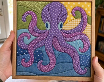 May include: A square fabric wall art piece in a light wood frame featuring a purple octopus with a white floral pattern. The background consists of quilted fabric sections in shades of green, yellow, and blue with various patterns like dots and swirls.