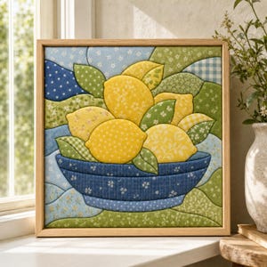 May include: A square framed fabric wall art piece featuring a patchwork design of yellow lemons in a blue bowl. The composition uses various patterned fabrics in shades of yellow, green, and blue to create a textured, quilted appearance.
