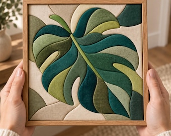 May include: A square wall art piece featuring a fabric-based monstera leaf design in various shades of green, including forest, olive, and lime, set against a cream-colored background, all encased in a light-toned wooden frame.