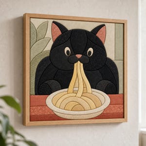 May include: A square fabric wall art piece in a light wood frame featuring a black cat with pink inner ears eating a bowl of yellow spaghetti. The background consists of muted green leaf shapes and a horizontal red surface under the bowl.
