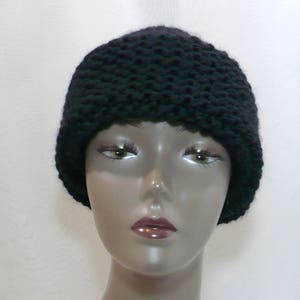 May include: A solid black beanie crafted with a chunky knit texture. The hat features a thick, rounded crown and a simple, unadorned design that fits snugly around the head. The yarn has a visible, raised stitch pattern throughout the entire piece.